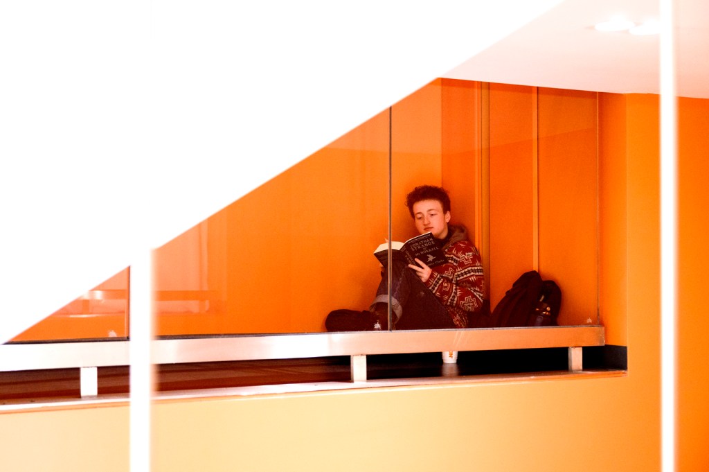 A person reads a book in an orange-colored room.