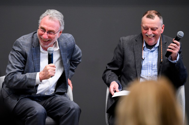 Marty Baron sitting next to another man, both holding microphones and laughing.