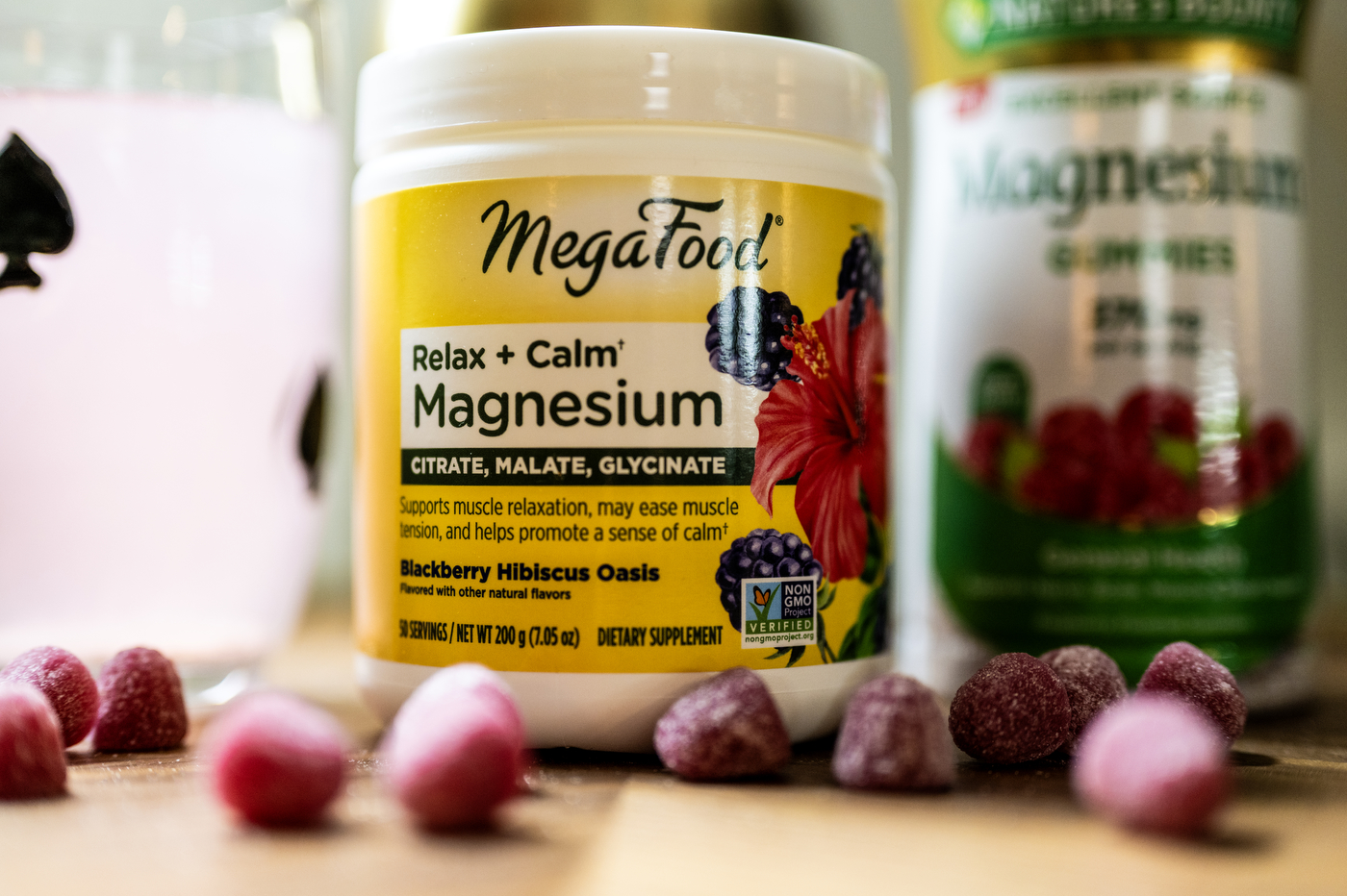 A container labeled "Relax + Calm Magnesium" is displayed in front of purple-colored gummies on a table.