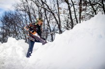 A person outside using a chainsaw to carve into snow and ice.
