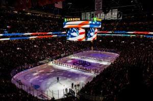 Inside of TD Garden with the lights down and the players lined up on the rink before the game.