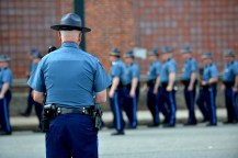 A MA state trooper seen from behind watching other state troopers stand in a line.