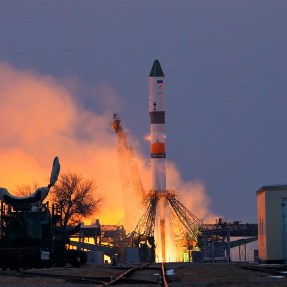 A rocket takes off from a base with smoke flying in all directions.