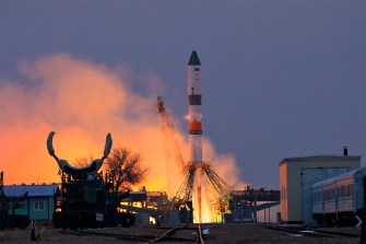 A rocket takes off from a base with smoke flying in all directions.