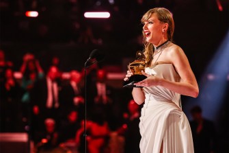 Taylor Swift holding a Grammy award on stage at the 2024 Grammys.
