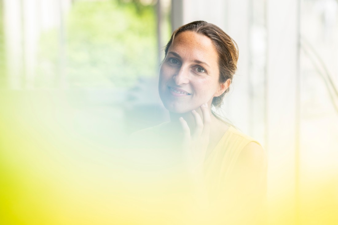 Headshot of Elettra Bietti wearing yellow in a warm-looking glass building.