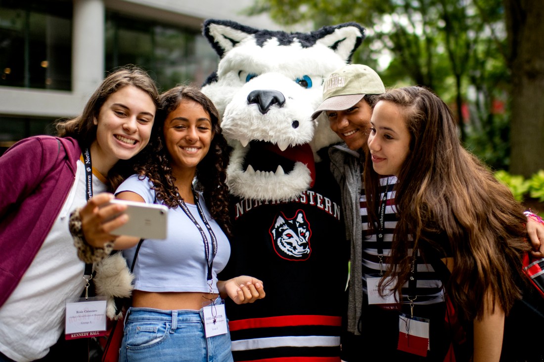 Four people pose with Northeastern's husky mascot, Paws.