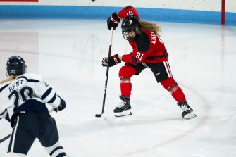 Northeastern womens hockey player taking a shot on net.