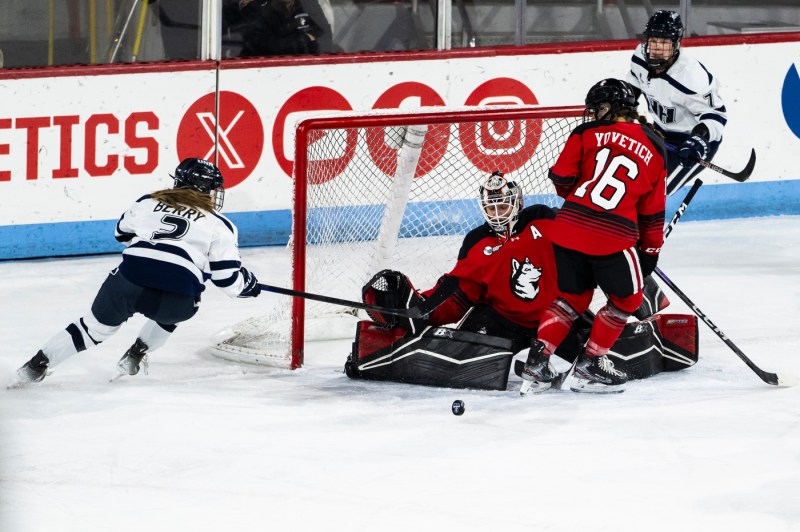 Northeastern womens hockey players defending the goal.