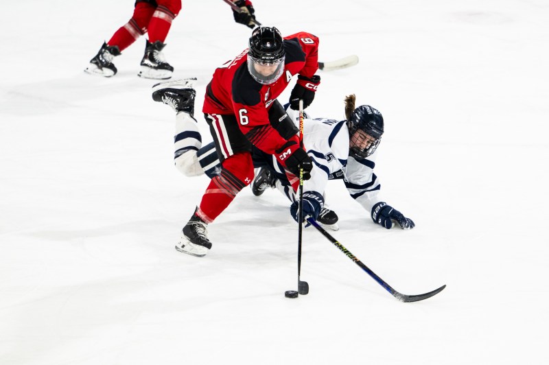 Northeastern womens hockey player defending the puck from a UNH player.