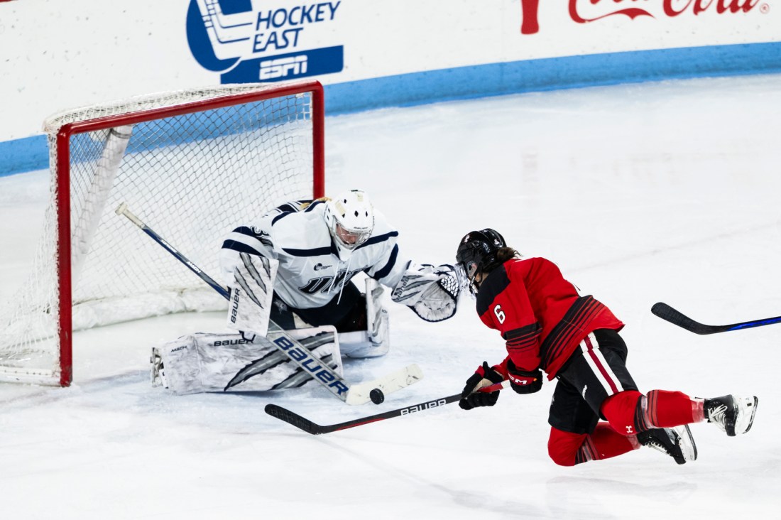 Northeastern women's hockey player flying through the air towards the goal. 