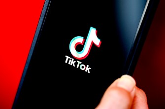 A person holding a phone displaying the TikTok loading screen.
