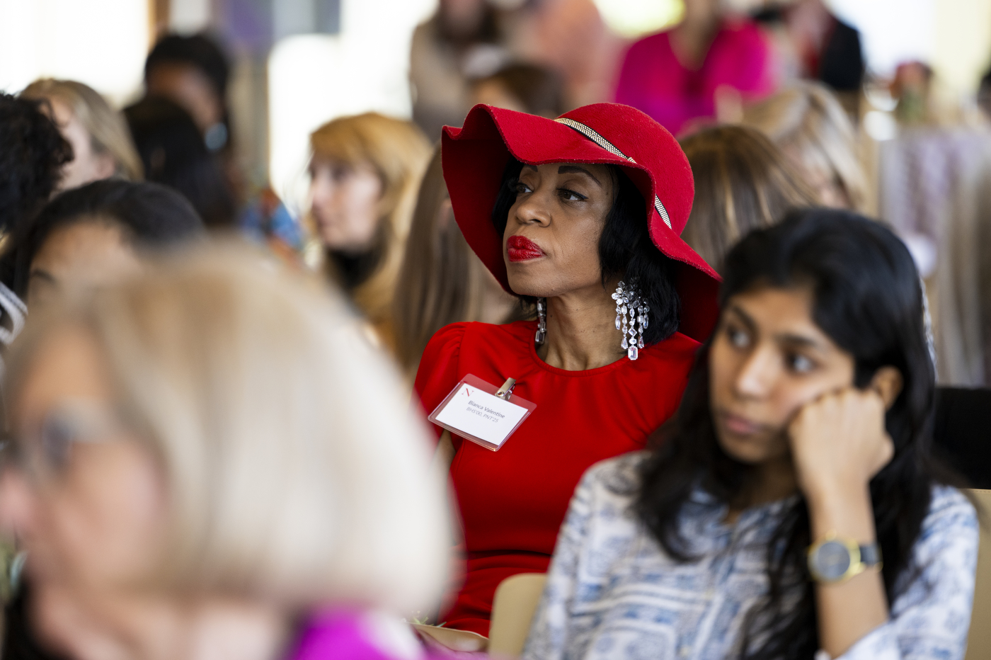 Audience member wearing red shirt and floppy red hat speaking at Women Who Empower event. 