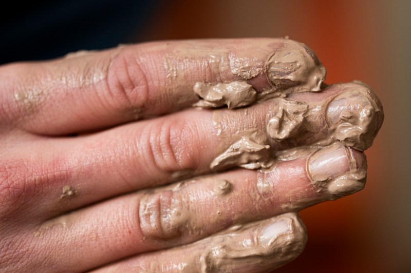 David Chatson's fingers covered in brown clay.