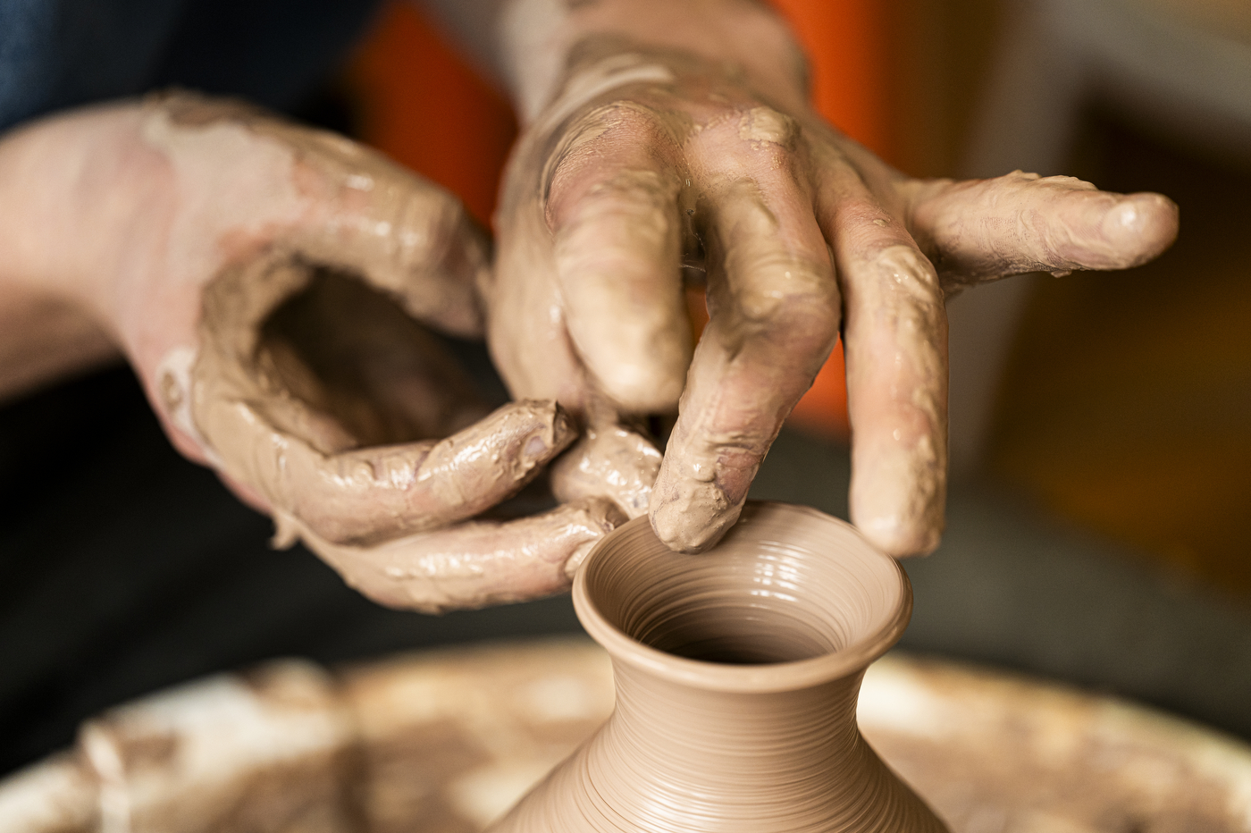 David Chatson pinching the top of a clay vase to make a lip.