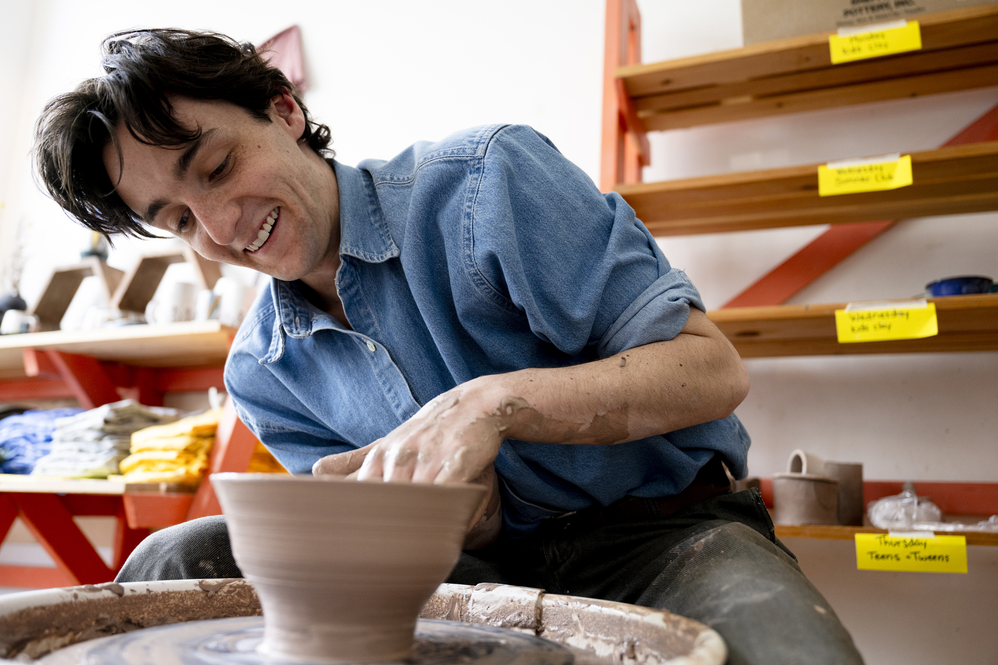David Chatson smiling while shaping clay on the wheel.