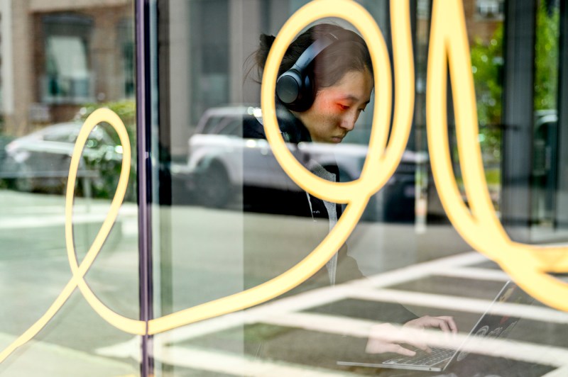 A person sits behind a window covered in a large, yellow looped illustration.