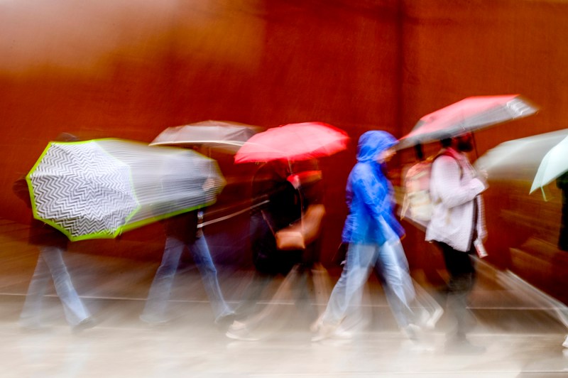 A blurred image of a tour group walking together outside on a rainy day.