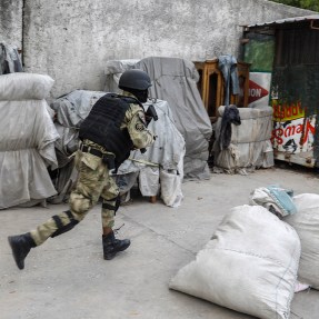 A police officer running during a gang operation in Haiti.