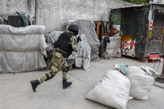 A police officer running during a gang operation in Haiti.