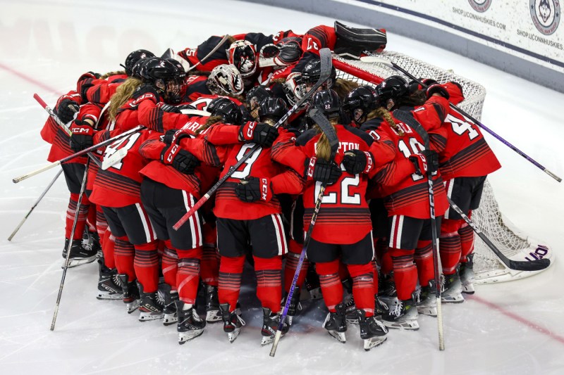 Womens hockey players huddled on the ice.