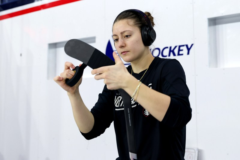 Womens hockey player taping her stick.