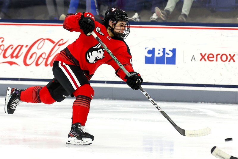 Northeastern womens hockey player shooting the puck.