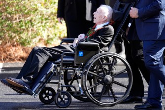 Jimmy Carter in a wheelchair leaving a funeral service.
