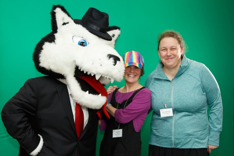 Paws posing in front of a green screen with two Northeastern employees.