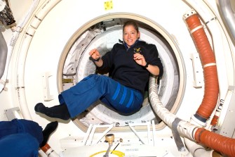 Pam Melroy floating in the docking compartment of a space shuttle.