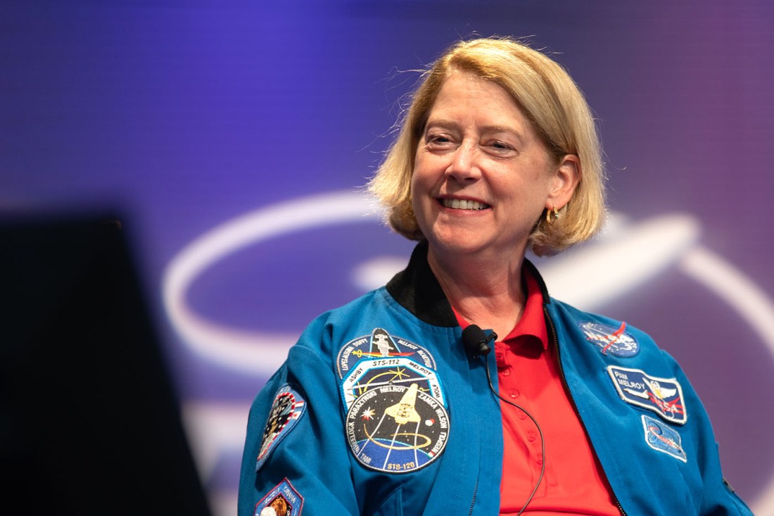 Pam Melroy wearing a NASA jacket and red shirt smiling.
