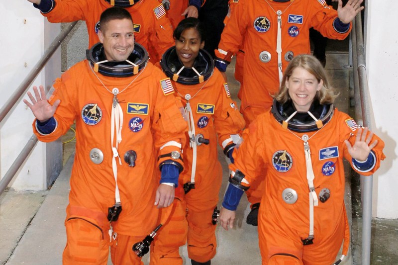 Pam Melroy and two other people in orange spacesuits. 