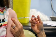 A person inserts a needle of a vaccine into a child's arm.