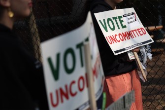 People holding 'Vote Uncommitted' signs outside of a polling location in Michigan.