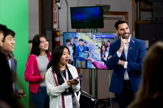 Multiple students stand in a news station's studio before a green screen for Northeastern's Entrepreneurship Treks program.
