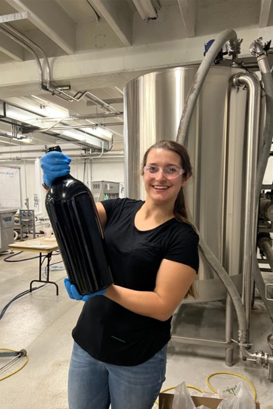 Grace Arents holding up a large bottle of wine.