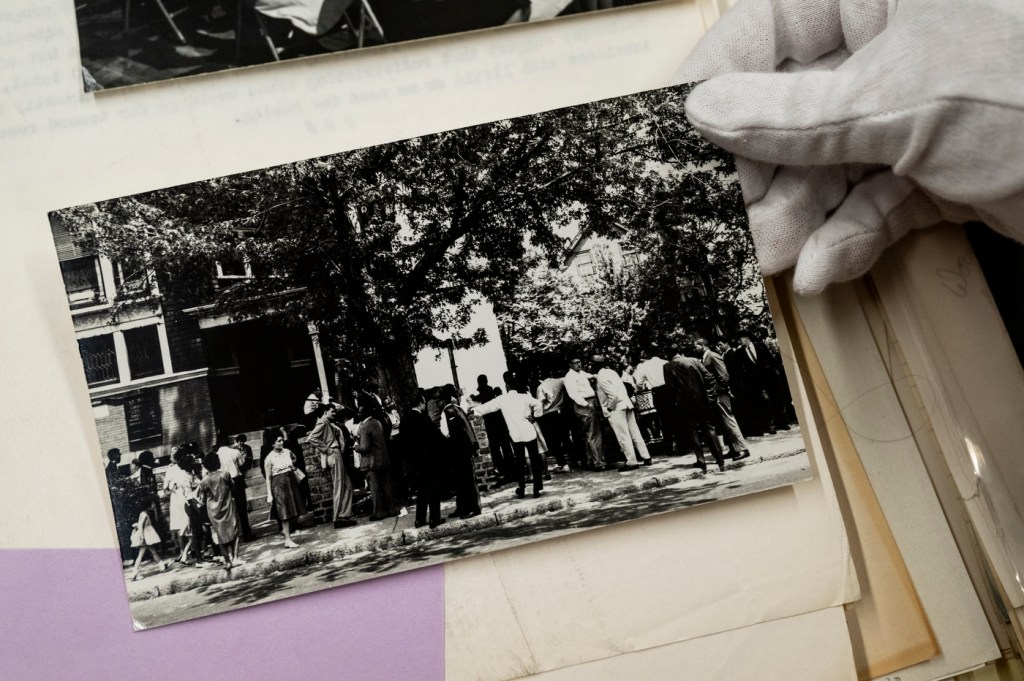 Molly Brown holding a black and white photo with a gloved hand.