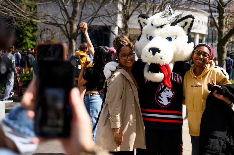 Paws mascot posing for a photo with two students. 