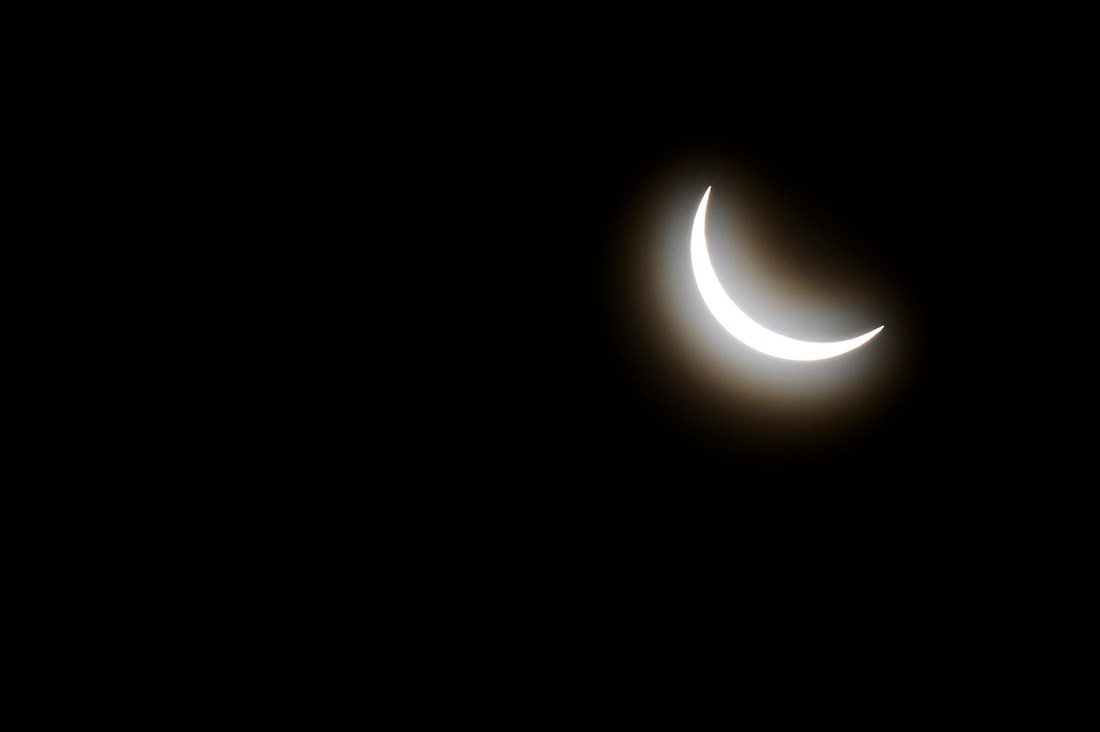 A crescent shape of the sun as it is blocked by the moon.