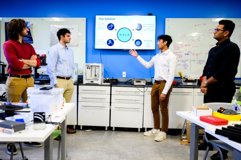Engineering team members gesturing to a presentation displayed on a TV.