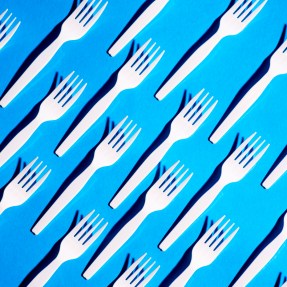 Plastic forks lined up on an angle on a blue background.
