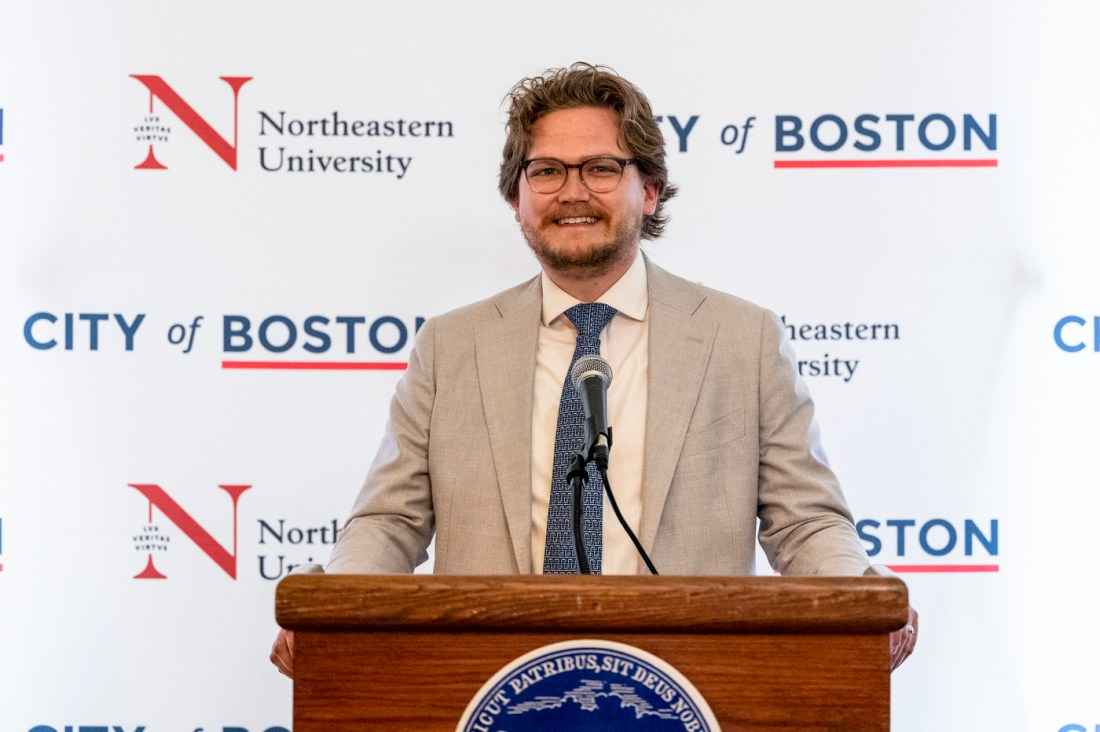 A Moakley scholar smiling in front of a podium at the reception.
