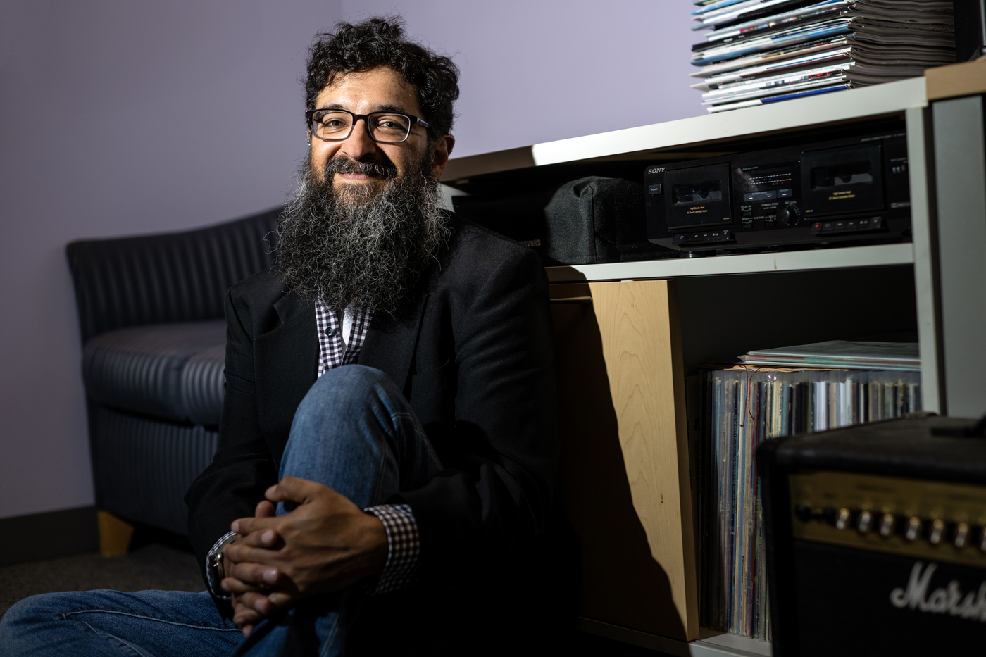 Andrew Mall, xan associate professor of music at Northeastern, sits against a massive collection of vinyl records.