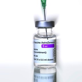 A vial of AstraZeneca vaccine with a syringe in it.