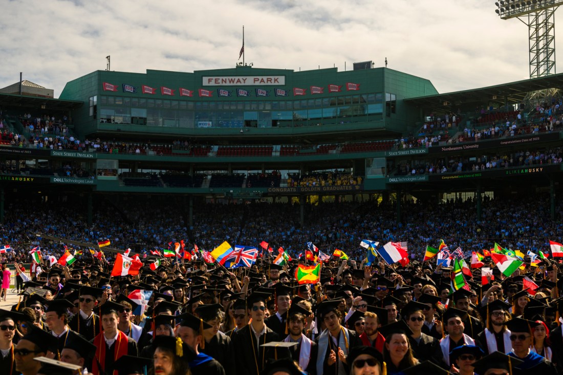 Graduates wave flags from all over the world in Fenway Park.
