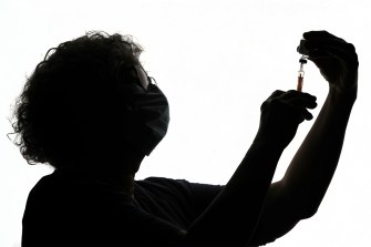 Silhouette of a person filling a syringe.