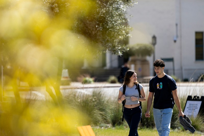 Two students walking outside in the sun.