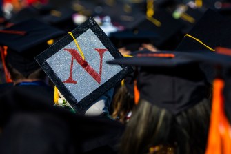A Northeastern graduate with a sparkly silver mortarboard and a red 'N' on it.
