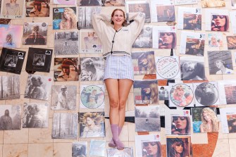 A Taylor Swift fan lying on the floor surrounded by dozens of different vinyl editions of Taylor Swift albums.