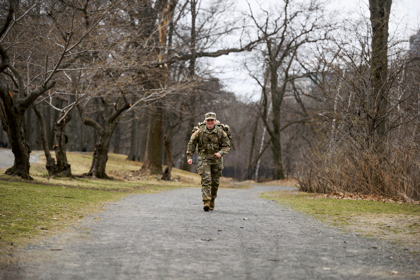 Kayla McCann running on a road, wearing a uniform and military backpack.
